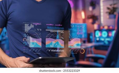 A young professional engages with an advanced tablet displaying vibrant data visualizations in a contemporary workspace full of color, representing technology and analytics.