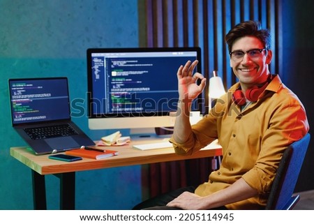 Young professional freelancer fun happy software engineer IT specialist programmer man wear shirt work at home writing code on laptop pc computer showing okay ok gesture. Program development concept