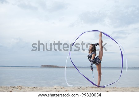 young professional gymnast woman dance with ribbon - outdoor sand beach