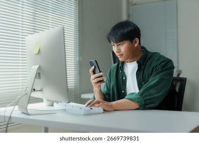 Young professional managing projects and multitasking using smartphone and computer in home office