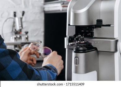 Young professional optometrist holding eye glasses in optician workshop. Production of lenses for glasses with special tools and equipment at opticians office