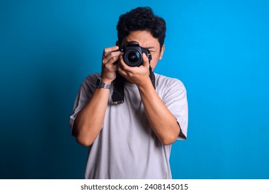 Young professional photographer in red shirt take picture of you using camera on blue background - Powered by Shutterstock