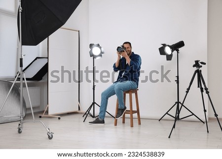 Young professional photographer taking picture in modern photo studio