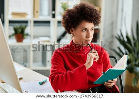 Young professional reflects thoughtfully while writing in a notebook at her desk.