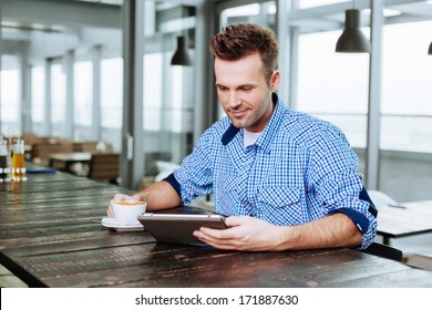 A Young Professional Sitting At Canteen Table With A Tablet