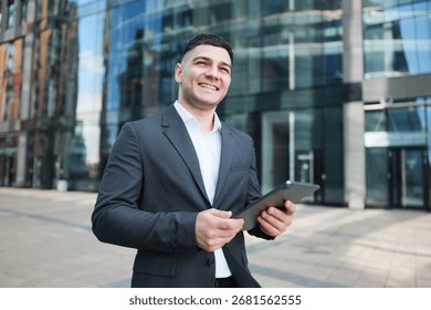 Young professional smiles while using tablet in urban business district