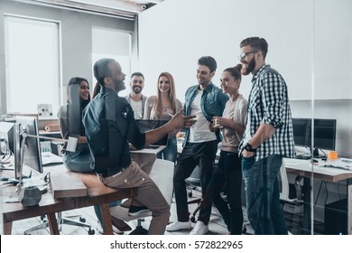 Young Professional Team.  Group Of Young Modern People In Smart Casual Wear Having A Brainstorm Meeting While Standing Behind The Glass Wall In The Creative Office