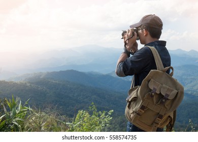 Young professional travrler man with camera shooting outdoor, fantastic mountain landscape.
