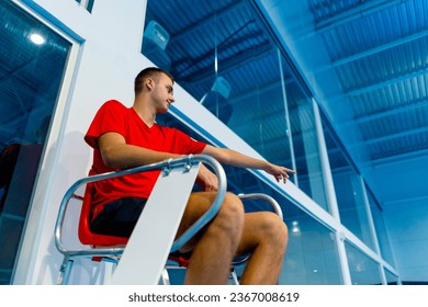young professional umpire in the game of tennis sitting on the observation tower and watching the championship or game pointing his hand at player