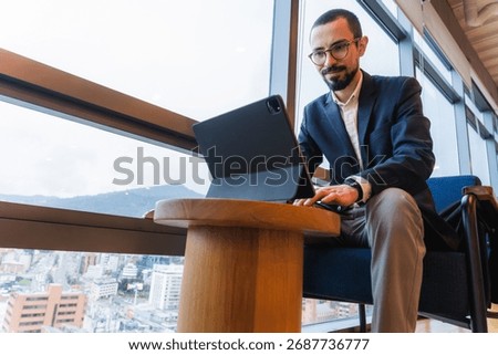Young professional using tablet by office window working remotely