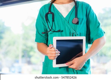 Young And Professional Woman Doctor With An IPad Showing Result Research Something Isolated On Hospital Background.