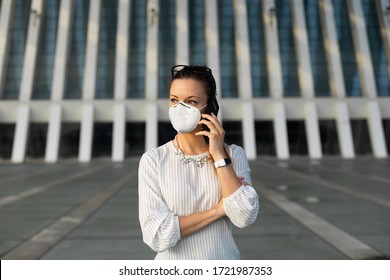 Young professional woman on cellphone business call outside under coronavirus Covid-19 health crisis. Business woman wearing facial mask for avoid infection.