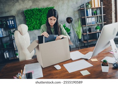 Young professional woman preparing her office desk, organizing workspace essentials in a box, showcasing productivity and elegance. - Powered by Shutterstock