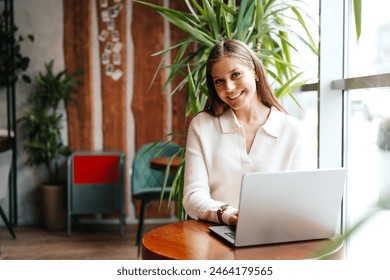 Young Professional Woman Working on Her Laptop at a Modern Cafe During Daytime - Powered by Shutterstock