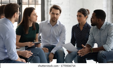 Young professionals company employees diverse staff members gather together sit on chairs brainstorming solving working moments having dispute express opinion point of view. Teamwork briefing activity - Shutterstock ID 1770506714