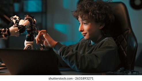 A young programmer celebrated as his toy robot came to life and reacted unpredictably. He had programmed it on a laptop and now watched with happiness and amazement.