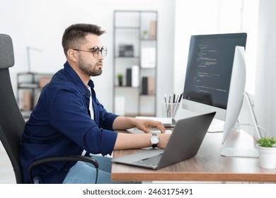 Young programmer working at desk in office