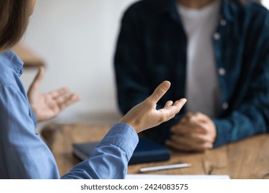 Young project leader woman in informal shirt telling business ideas to business colleague, sitting at work table, meeting with startup partner, talking, explaining strategy. Cropped shot, close up - Powered by Shutterstock