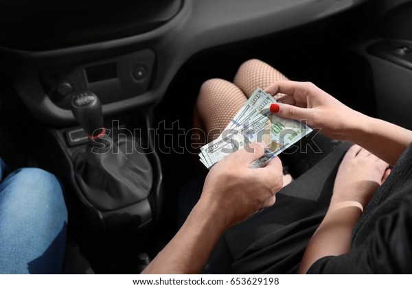Young\
prostitute receiving money from client in\
car