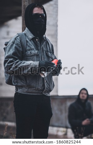 Young protesters group getting ready to make graffiti on the abandoned building. Modern styled urban hooligans.