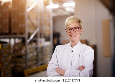 Young proud happy female worker is holding her arms crossed and smiling for the camera in cargo storage area. - Shutterstock ID 1112417771
