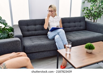 Young Psychologist Woman At Consultation Office Smelling Something Stinky And Disgusting, Intolerable Smell, Holding Breath With Fingers On Nose. Bad Smell 