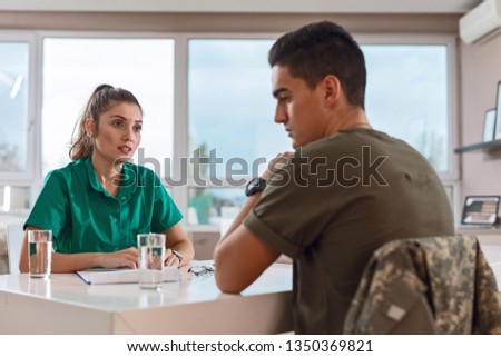 Young psychotherapist talking to army solider who is suffering form post-traumatic stress disorder at doctor's office. 