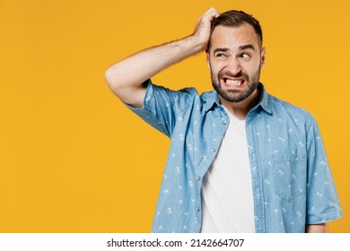 Young puzzled embarrassed bewildered caucasian man 20s wearing blue shirt white t-shirt scratch head look aside say oops isolated on plain yellow background studio portrait. People lifestyle concept - Shutterstock ID 2142664707
