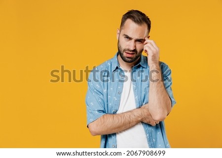 Young puzzled embarrassed bewildered caucasian man 20s wearing blue shirt white t-shirt prop up forehead hold head say oops isolated on plain yellow background studio portrait People lifestyle concept