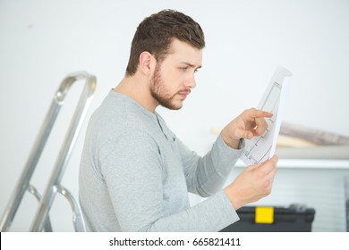 Young Puzzled Man Reading Assembly Instructions