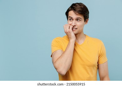 Young puzzled mistaken minded worried confused man 20s wear yellow t-shirt look aside on workspace copy space area biting nails fingers isolated on plain pastel light blue background studio portrait. - Shutterstock ID 2150055915