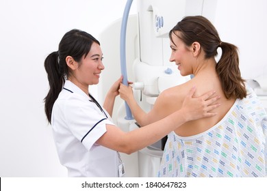 A Young Qualified Radiologist In White Uniform Attending Her Patient On A Mammogram Machine In The Radiology Department