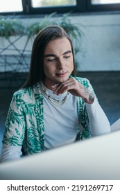 Young Queer Designer Using Blurred Computer In Office