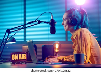 Jovem apresentadora de rádio trabalhando no estúdio, ela está sorrindo e transmitindo anúncios