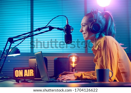 Young radio host working in the studio, she is smiling and broadcasting announcements