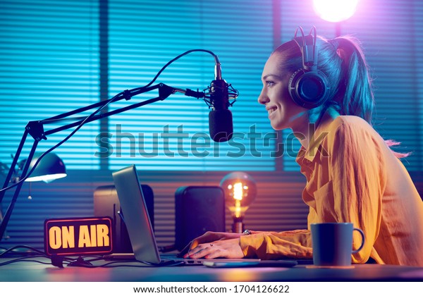 Young radio host working in the studio, she\
is smiling and broadcasting\
announcements