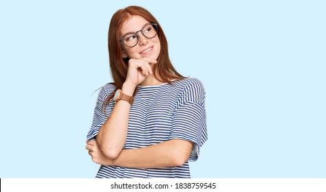 Young Read Head Woman Wearing Casual Clothes And Glasses With Hand On Chin Thinking About Question, Pensive Expression. Smiling And Thoughtful Face. Doubt Concept. 