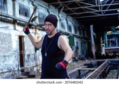 Young Rebel In Abandoned Factory Hall With A Metal Bar In His Hand, Threatening And Looking With Hatred At The Camera. Long Exposure Motion Blur Effect. Selective Focus.