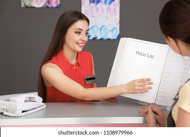 Young Receptionist Showing Price List To Client In Beauty Salon