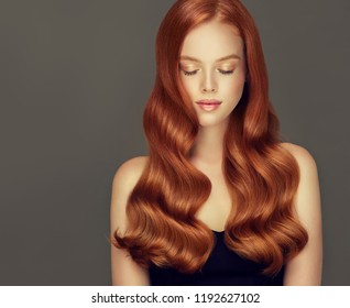 Young, red haired woman with voluminous hair.Beautiful model with long, dense, curly hairstyle .
