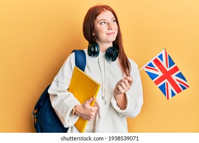 Young Red Head Girl Exchange Student Holding Uk Flag Smiling Looking To The Side And Staring Away Thinking. 