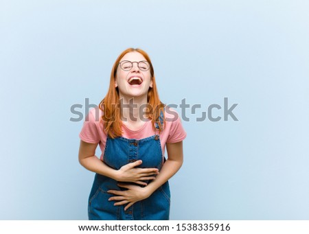 young red head pretty woman laughing out loud at some hilarious joke, feeling happy and cheerful, having fun