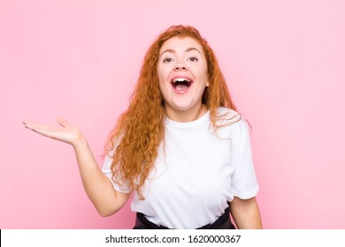 young red head woman feeling happy, surprised and cheerful, smiling with positive attitude, realizing a solution or idea against pink wall - Shutterstock ID 1620000367