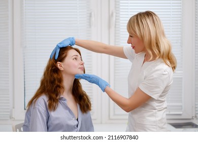 A young red-haired beautiful girl undergoes a medical examination in a cosmetology clinic. A female dermatologist consultation. Close up. - Shutterstock ID 2116907840