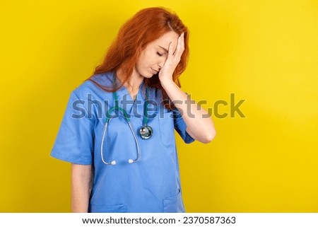 young red-haired doctor woman over yellow studio background with sad expression covering face with hands while crying. Depression concept.