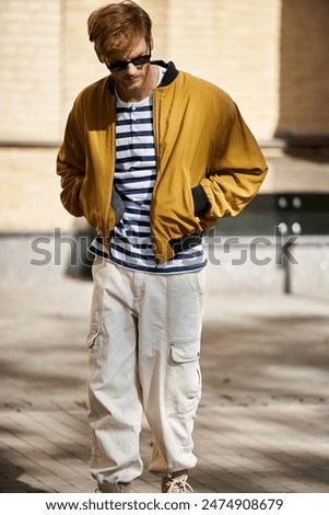 A young red-haired man strolling through the city in debonair attire.