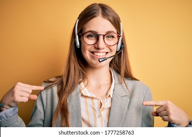 Young redhead call center agent woman overworked wearing glasses using headset looking confident with smile on face, pointing oneself with fingers proud and happy.