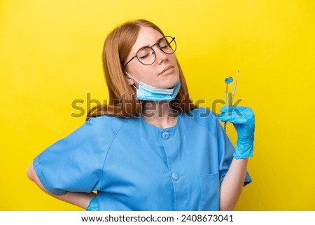 Young redhead Dentist woman isolated on yellow background suffering from backache for having made an effort