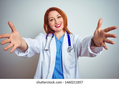 Young Redhead Doctor Woman Using Stethoscope Over White Isolated Background Looking At The Camera Smiling With Open Arms For Hug. Cheerful Expression Embracing Happiness.