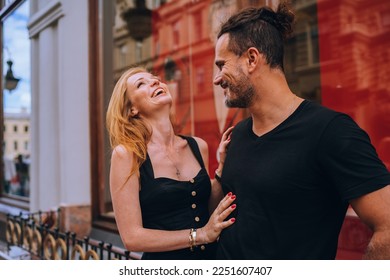 Young redhead European woman laughing touching boyfriend outdoors. Handsome Hispanic  man dating with girl on valentine's day. Pretty American girl giggling after fiancé’s joke. Romance, honeymoon.
